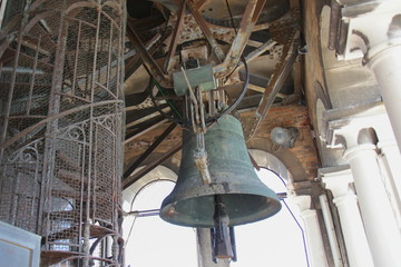 Bell under the ceiling of the old tower, visible spiral metal staircase