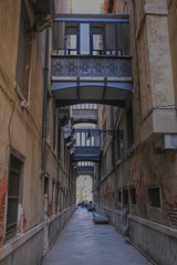 Very narrow street in Venice, two houses connected by balconies and walkways, bottom view