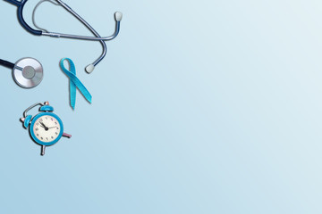 Blue ribbon with stethoscope and alarm clock on a blue background. World diabetes day concept. Top view with copy space.