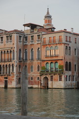 Wooden column of the pier, water of the Grand Canal, a typical house on the water in Venice, the evening sun sets