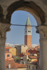 View of Venice from the tower of the Palace of Contarini del Bovolo, selected focus - columns from the arch-window in defocus, buildings and the tower in the distance in focus.