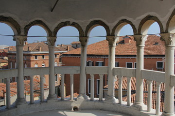 View of Venice from the tower of the Palace of Contarini del Bovolo, high point, selected focus - columns from the arch-window in defocus, buildings, roofs and tower in the distance in focus.