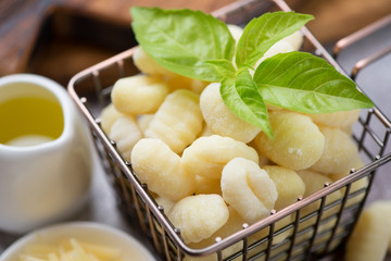 Close-up of raw potato gnocchi with fresh green basil leaves, selective focus