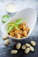 Bowl of potato gnocchi with sun dried tomatoes pesto, vertical shot on a grey stone background