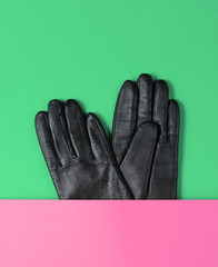 Half leather gloves on pink green paper background. Minimalism creative fashion concept. Top view