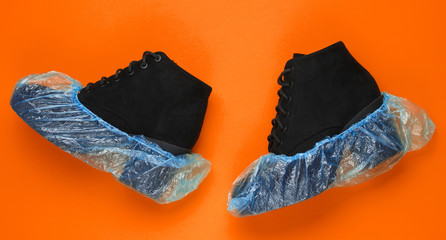 Black suede boots with shoe covers on orange background. Over view
