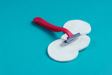 Beauty still life, minimalism. Plastic epilator razor with cotton circles on blue background. Women's accessories for beauty care.