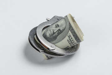 Steel handcuffs and one hundred dollar bills on a white background. Crime, corruption concept