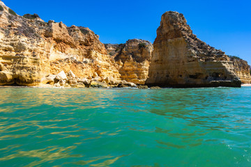 Fototapeta na wymiar Turquoise sea waters and the sandstone cliffs of Praia da Marinha seen from a boat, Lagoa, Algarve, Portugal