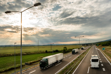 Lorry trucks in line as a caravan or convoy  on country highway under a beautiful sky
