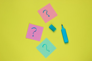 Memo pieces of paper with drawn question marks, felt-tip pen on green background. Top view