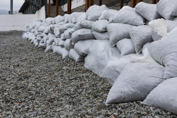 Stack of nylon bags with stones. Pebble bags fortification wall. Winter storm and flood defense...
