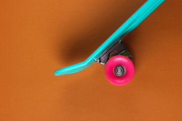 Plastic mini cruiser board on brown background. Pastel color trend. Summer fun. Youth minimalistic...