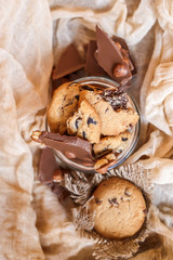 Shortbread chocolate cookies and a glass of milk on a brown background.  Milk chocolate with nuts and cookies.