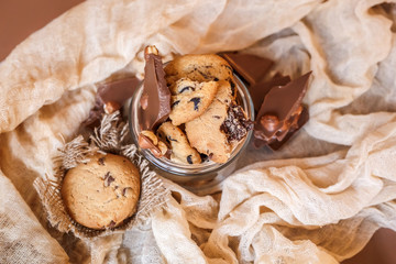 Shortbread chocolate cookies and a glass of milk on a brown background.  Milk chocolate with nuts and cookies.