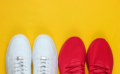 Two pairs of sneakers on a yellow background. White and red shoes. Top view