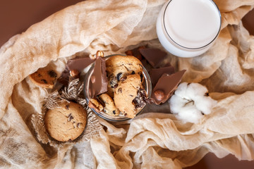 Shortbread chocolate cookies and a glass of milk on a brown background.  Milk chocolate with nuts and cookies.