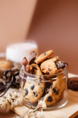 Shortbread chocolate cookies and a glass of milk on a brown background.  Milk chocolate with nuts and cookies.