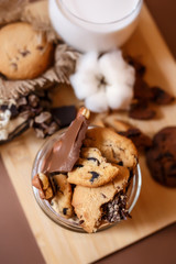 Obraz na płótnie Canvas Shortbread chocolate cookies and a glass of milk on a brown background. Milk chocolate with nuts and cookies.