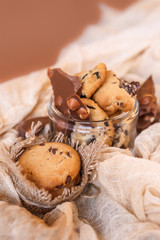 Shortbread chocolate cookies and a glass of milk on a brown background.  Milk chocolate with nuts and cookies.