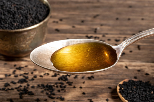 Black cumin seed oil on a spoon and black cumin seeds