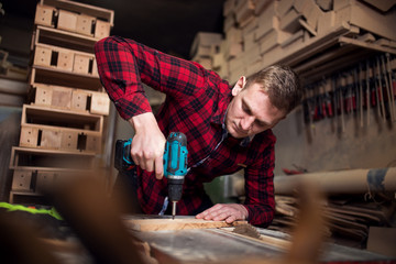 Young carpenter working with drill in workshop
