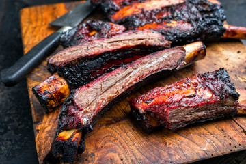 Barbecue burnt chuck beef ribs marinated with hot chili sauce sliced as closeup on an old rustic...