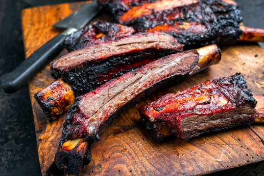 Barbecue burnt chuck beef ribs marinated with hot chili sauce sliced as closeup on an old rustic wooden cutting board