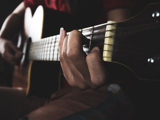 Fototapeta premium Woman playing acoustic guitar focusing on hand holding C major chords