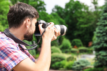 Fototapeta na wymiar Photographer taking photo with professional camera in park