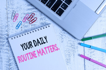 Handwriting text Your Daily Routine Matters. Conceptual photo Have good habits to live a healthy life Slim metallic laptop blank spiral notepad pens clips lying wooden table