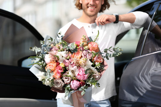 Man with beautiful flower bouquet near car on street, closeup