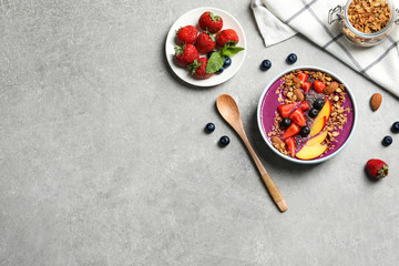 Delicious acai smoothie with granola and berries served on grey table, flat lay. Space for text