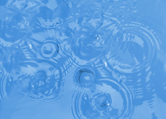 Splash of blue water with drops as background, top view