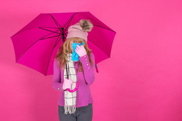cold woman with handkerchief and umbrella on color background