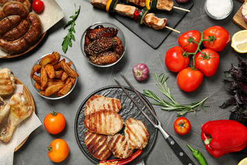 Flat lay composition with barbecued meat and vegetables on grey table