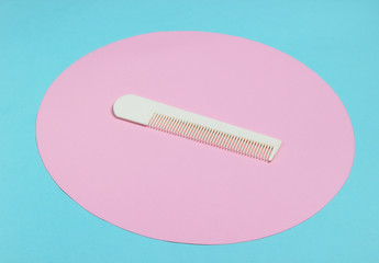 White Hair combon on blue pastel background with pink pastel circle. Creative minimalistic beauty and fashion still life. Top view