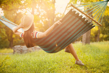 Young woman resting in comfortable hammock at green garden