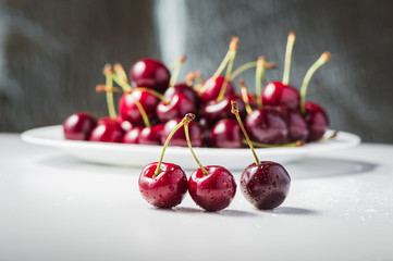Red cherry berry on the table, water, droplets of water. Fresh fruit is useful in a plate. Food for vegetarians.