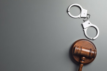 Judge's gavel and handcuffs on grey background, flat lay with space for text. Criminal law concept