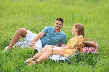 Happy young couple having picnic on green grass in park