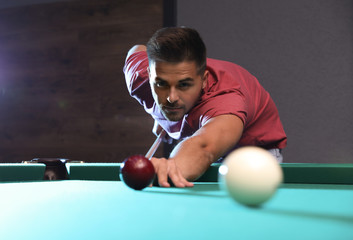 Handsome young man playing Russian billiard indoors