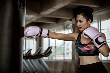 Fototapeta na wymiar Beautiful Asian women are punching sandbags in the gym, exercise ideas, weight loss, muscle building and self defense.