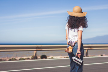 Filmmaker waiting for the opportunity to film with her 8 mm film camera next to a road