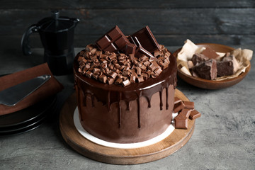 Freshly made delicious chocolate cake on grey table against black background