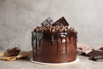 Freshly made delicious chocolate cake on marble table against grey background