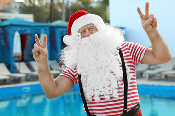 Obraz premium Authentic Santa Claus having fun near pool at resort