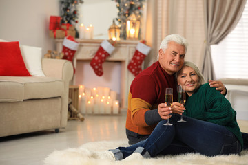 Happy mature couple with glasses of champagne at home. Christmas celebration