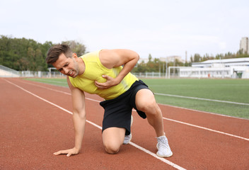 Obraz premium Young man having heart attack while running at stadium