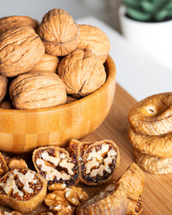 Whole walnuts in bowl. Dried figs with walnuts on wooden background.